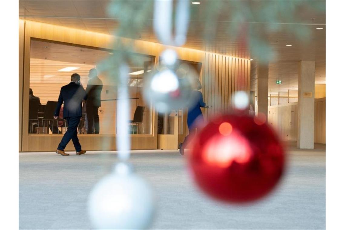 Abgeordnete des Landtags von Baden-Württemberg gehen während der letzten Plenarsitzung vor Weihnachten an einem mit Christbaumkugeln geschmückten Weihnachtsbaum vorbei. Foto: Bernd Weißbrod/dpa