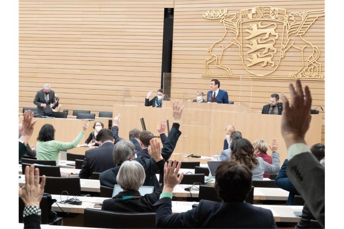 Abgeordnete heben im Landtag von Baden-Württemberg die Hände und stimmen den Haushalt für das Jahr 2022 ab. Foto: Nicole Eyberger/dpa