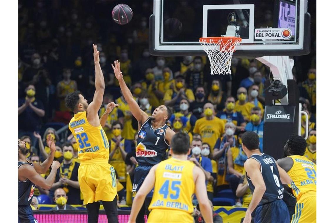 Albas Johannes Thiemann (l) versenkt den Ball gegen Crailsheims Jaren Lewis im Basketball Pokalfinale zwischen Alba Berlin - Merlins Crailsheim. Foto: Jörg Carstensen/dpa