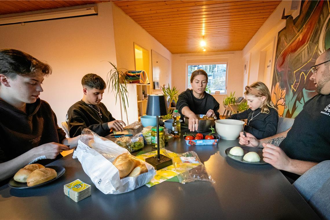 Am Esstisch erledigen Tim, Ashour, Studentin Nadine Arnold, Emilia und Sozialarbeiter René Schilke (von links) die Vorarbeiten für das gemeinsame Mahl: Sie schneiden die Brötchen auf, schnippeln Tomaten, Zwiebeln und Kartoffeln. Fotos: Alexander Becher 