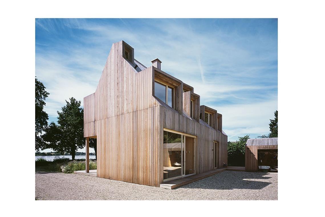 An der Schlei, einem Meeresarm der Ostsee, ist diese Wohnskulptur  zu finden. Das Holz wurde sägerau und unbehandelt verwendet. Entworfen wurde das Haus mit Zugang zum Wasser von dem  Architekten Charles de Picciotto aus Hamburg für sechs Bewohner. Elf Gauben  . . .