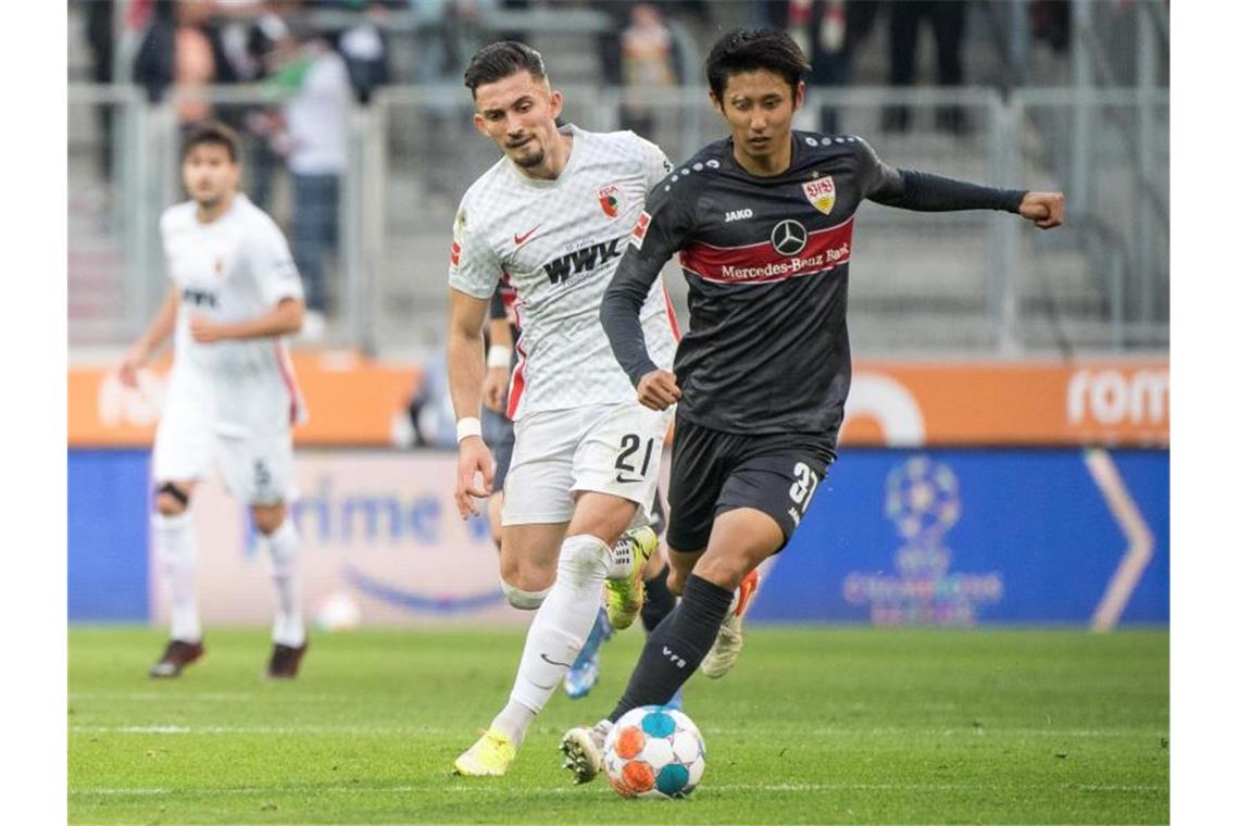 Andi Zeqiri von Augsburg (l) und Hiroki Ito von Stuttgart im Zweikampf um den Ball. Foto: Matthias Balk/dpa