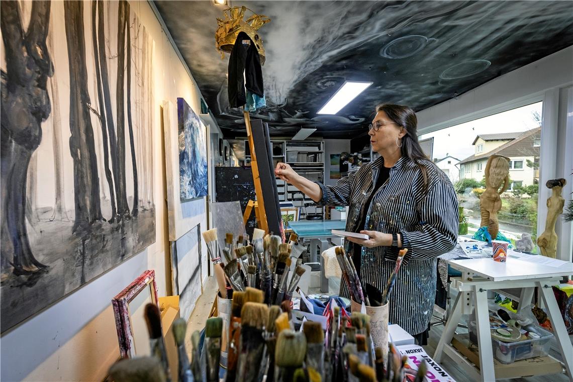 Andrea Blum in ihrem Backnanger Atelier. An der Wand hängen „Wald“- und „Wasser“-Bilder, im Hintergrund ist die Meerjungfrau zu erkennen. Fotos: Alexander Becher