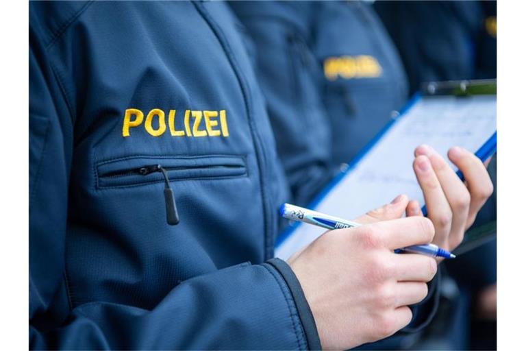 Angehende Streifenpolizisten notieren sich in einer Polizeischule etwas auf einer Notizmappe. Foto: Lino Mirgeler/dpa/Archivbild