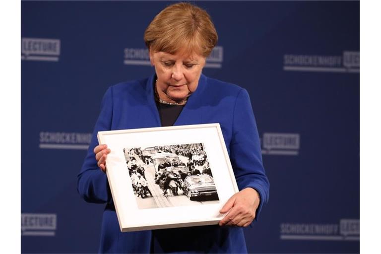Angela Merkel (CDU) hält bei der Premiere der Dr. Andreas Schockenhoff-Lecture ein Foto, das ihr geschenkt wurde. Foto: Karl-Josef Hildenbrand