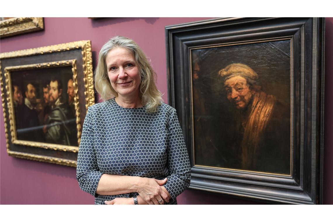 Anja Sevcik steht zwischen einem Selbstbildnis von Peter Paul Rubens unter Freunden (links) und einem Selbstbildnis von Rembrandt (rechts).