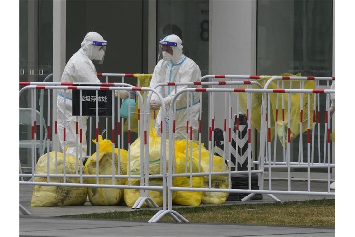 Zahl der Corona-Fälle in China schnellt in die Höhe Arbeiter desinfizieren sich gegenseitig, nachdem sie in Kontakt mit Müllsäcken gekommen sind, die in Bürogebäuden mit Corona-Fällen gefunden wurden. Foto: Ng Han Guan/AP/dpa