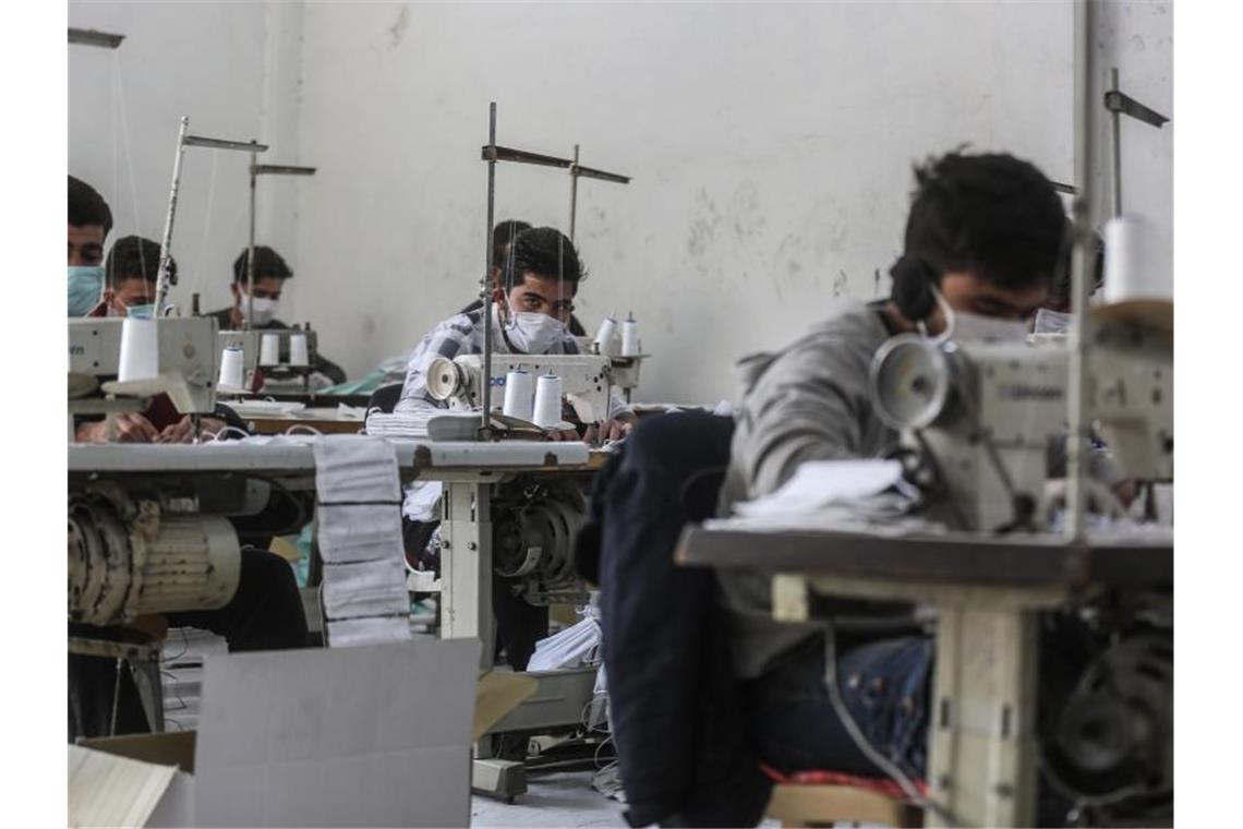 EU unterstützt Aufruf zur Waffenruhe in Syrien Arbeiter in der umkämpften Region Idlib mit Gesichtsmasken. In einem kleinen Labor stellen sie notdürftig Schutzmasken her. Foto: Anas Alkharboutli/dpa