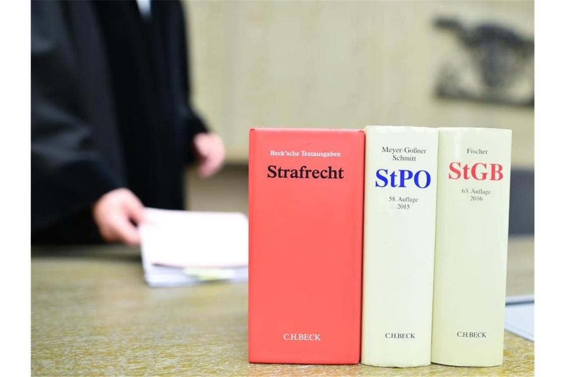 Auf der Richterbank in einem Verhandlungssaal steht eine Reihe Strafgesetzbücher. Foto: Uwe Anspach/dpa/Archivbild