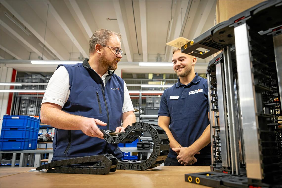 Ausbildungsleiter Kristian Mertlik bespricht mit Azubi Frederik Eimer einen Auftrag. In solchen Energieketten, die Murrplastik produziert, verlaufen zum Beispiel in Maschinen und Waschanlagen die Kabel. Foto: Alexander Becher