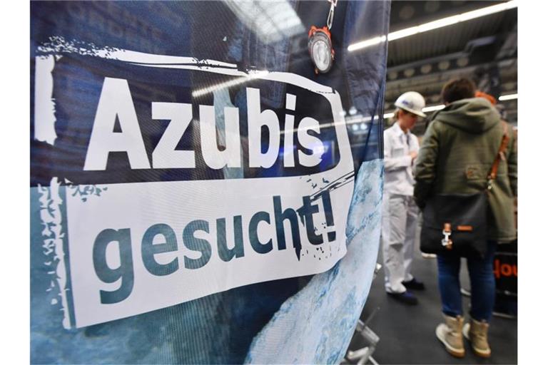 „Azubis gesucht“ steht auf einem Banner am Stand einer Firma. Foto: Martin Schutt/zb/dpa/Archivbild