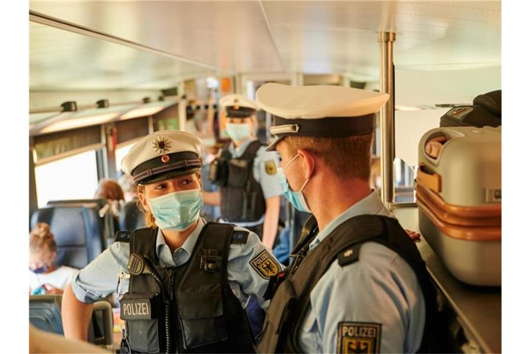 Beamte der Bundespolizei und Mitarbeiter der DB Sicherheit kontrollieren in einem ICb die coronabedingte Maskenpflicht. Foto: Annette Riedl/dpa