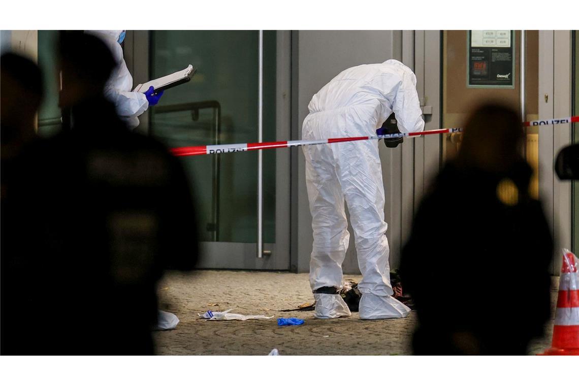 Beamte in weißen Schutzanzügen fotografieren blutige Kleidungsstücke und zertrümmerte Glasscheiben.