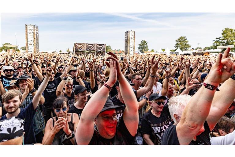 Besucher des Wacken Open Air feiern vor der Bühne während des Auftritts der Wacken Firefighters, die mit ihrem Konzert das Festival eröffneten.