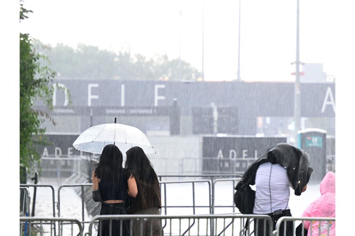 Besucher gehen im Regen vor einem Eingang des ersten von zehn Konzerten der britischen Sängerin Adele in München.