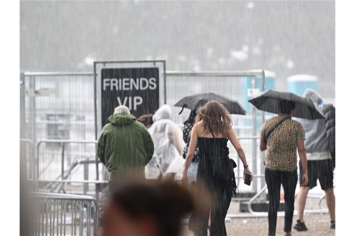 Besucher gehen im Regen vor einem Eingang des ersten von zehn Konzerten der britischen Sängerin Adele in München.