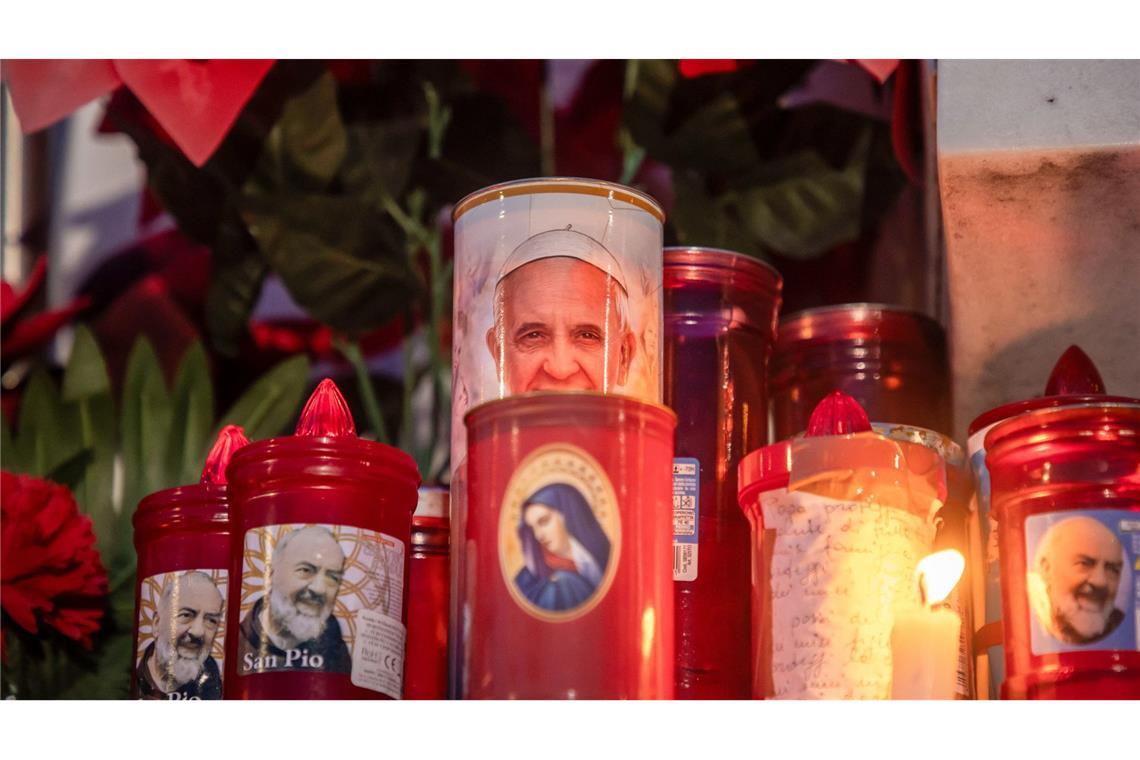 Blumen und Votivkerzen, einige mit dem Abbild von Papst Franziskus, liegen vor dem Gemelli-Krankenhaus in Rom.