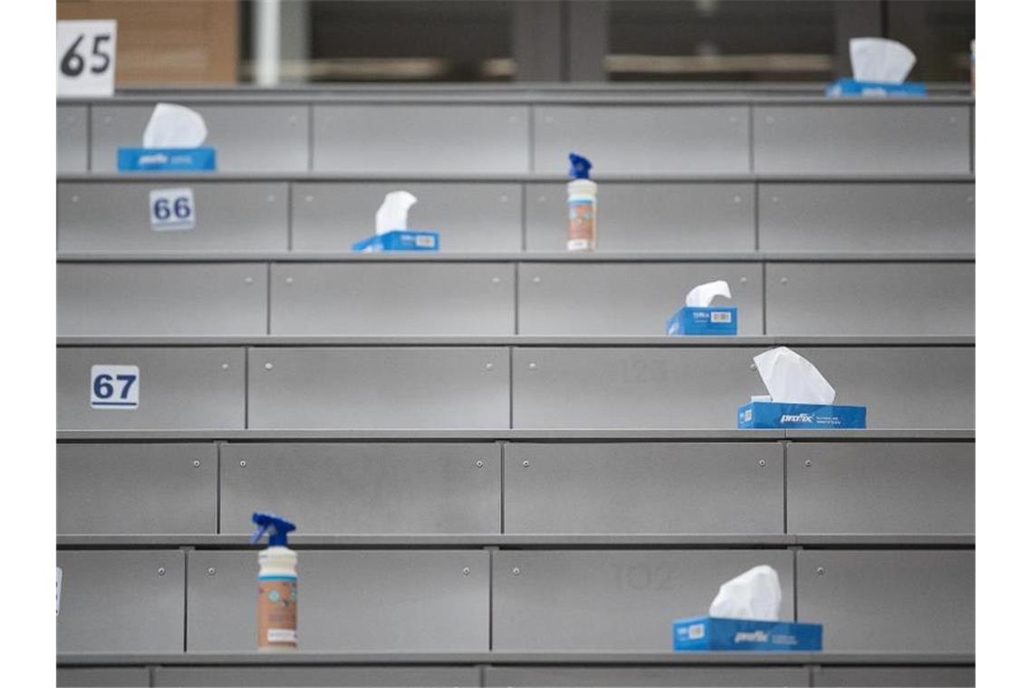 Prüfungen: Lehre für Studierende wieder in Präsenz möglich Boxen mit Papiertüchern und Sprühflaschen mit Desinfektionsmittel stehen in einem Hörsaal. Foto: Sebastian Gollnow/dpa/Archivbild