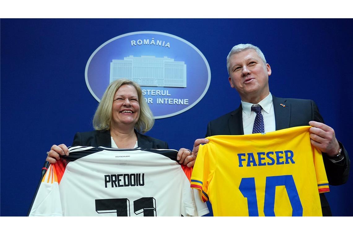Bundesinnenministerin Nancy Faeser und ihr rumänischer Amtskollege Marian Catalin Predoiu halten nach einer gemeinsamen Pressekonferenz Trikots der jeweiligen Fussball-Nationalmannschaft in den Händen.