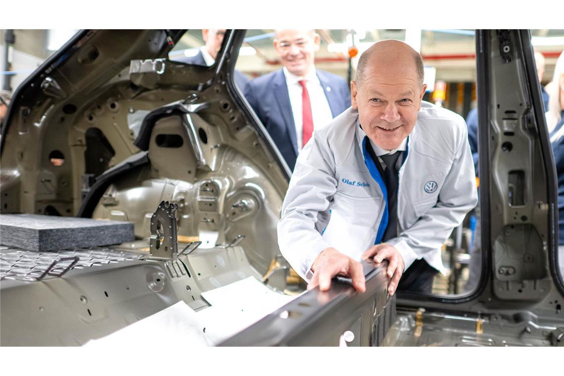 Bundeskanzler Olaf Scholz legt im VW-Werk Emden eine Dämmmatte in einen Wagen.