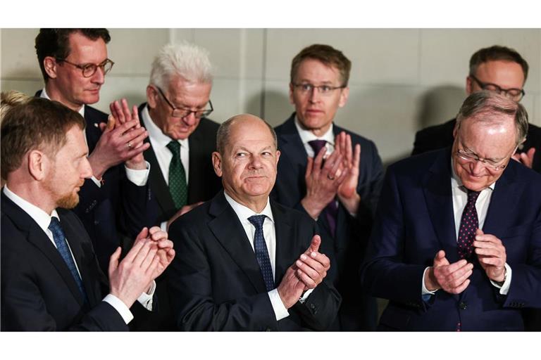 Bundeskanzler Olaf Scholz (M, SPD) applaudiert zwischen den Ministerpräsidenten.