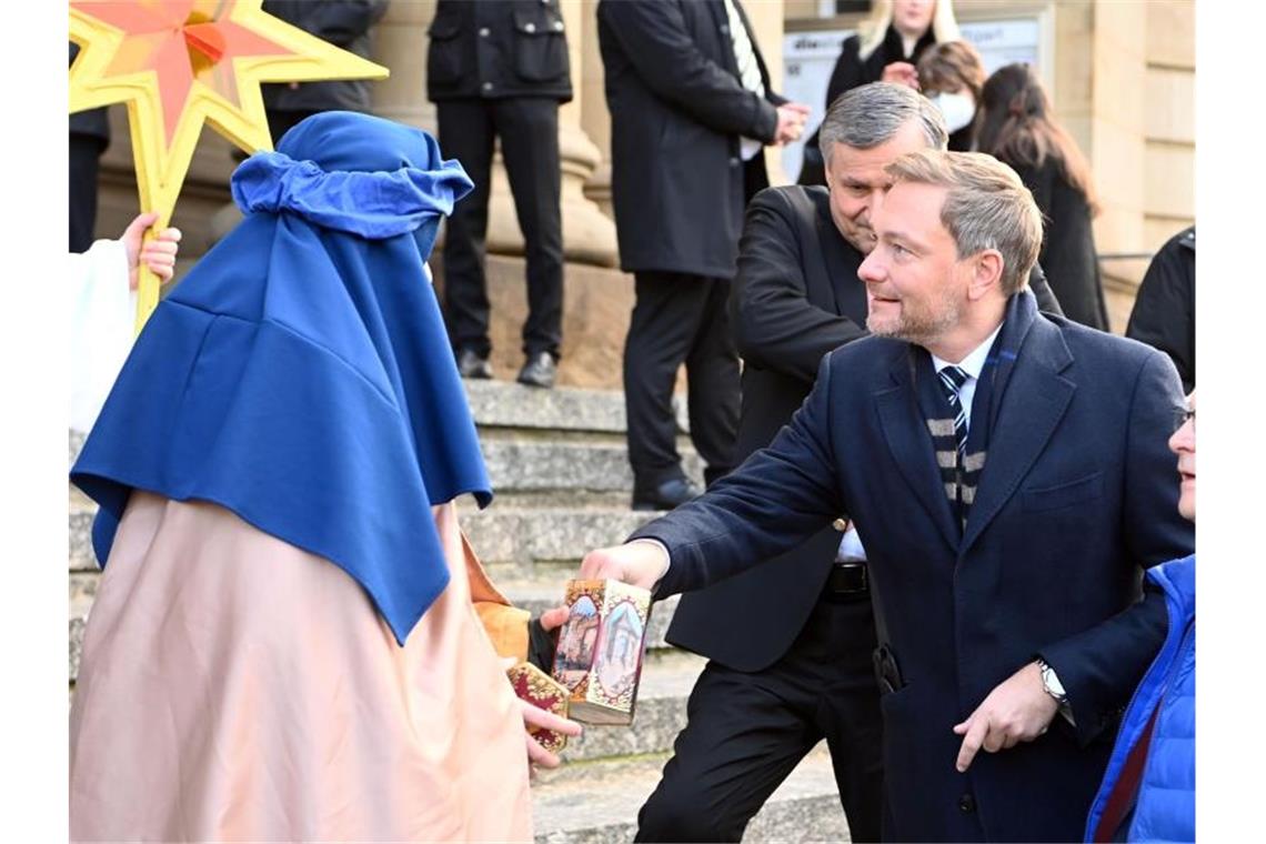 Christian Lindner wirft beim Dreikönigstreffen der FDP Geld in eine Schatulle von Sternsingern. Foto: Uli Deck/dpa