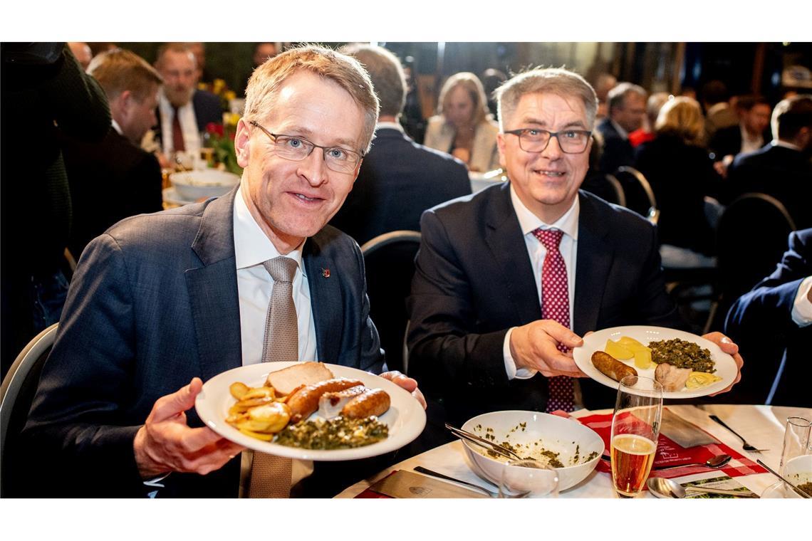 Daniel Günther (l), der Ministerpräsident von Schleswig-Holstein, ist der neue Oldenburger Grünkohlkönig. Hier beim Essen mit dem Oldenburger Oberbürgermeister Jürgen Krogmann (SPD). Auf den Tellern haben sie eine Portion Grünkohl und den klassischen Beilagen Kartoffeln, Pinkel, Kochwurst und Kassler.