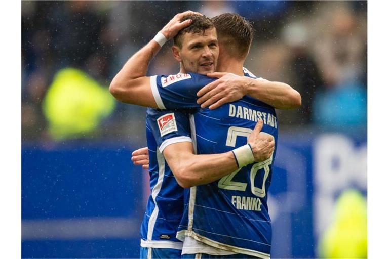 Darmstadts Mathias Wittek (l) und Marcel Franke umarmen sich nach dem Spiel. Foto: Axel Heimken/dpa/Archivbild