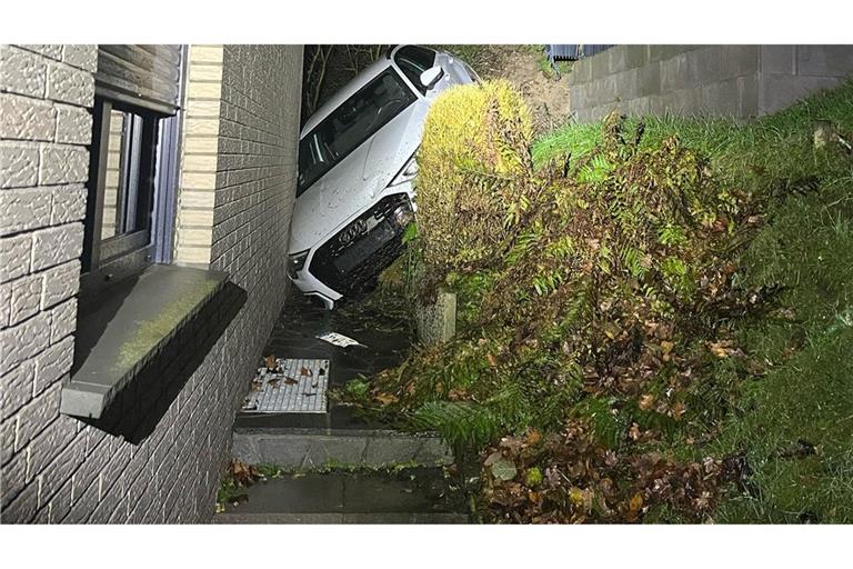 Das Auto steckt zwischen einem Abhang und dem verklinkerten Wohnhaus fest.