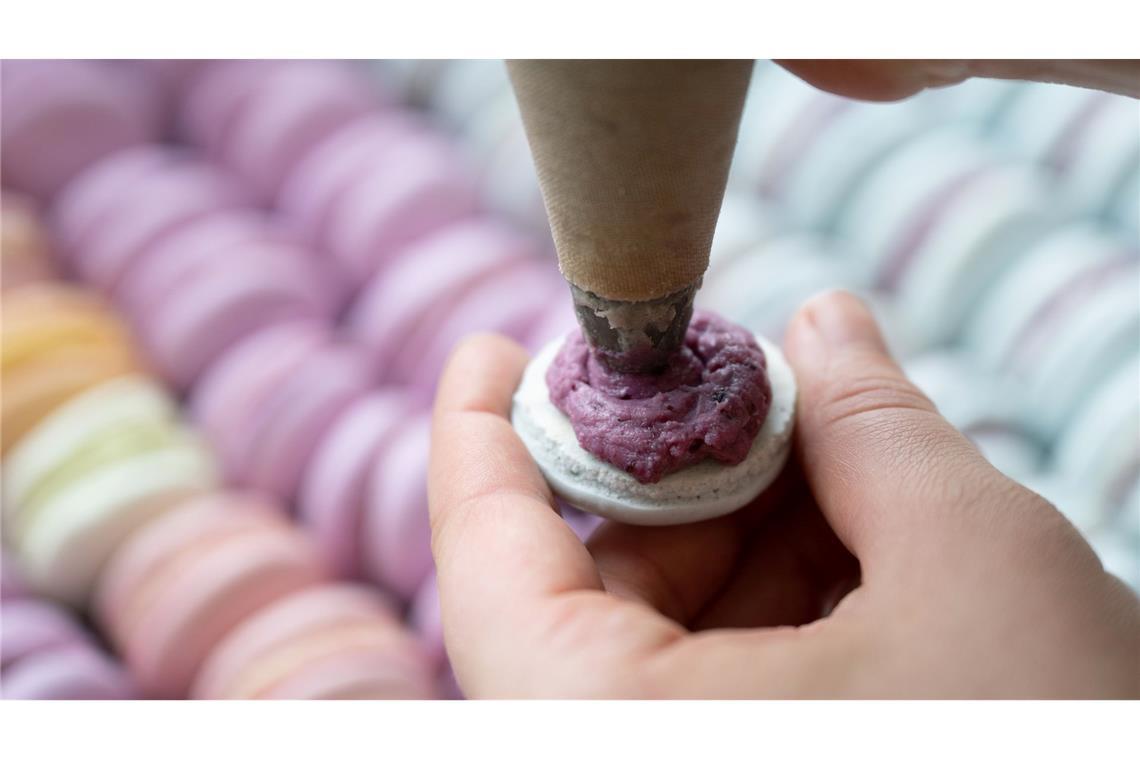 Das Baisergebäck Macaron wird in einer Bäckerei mit einer Spritztüte befüllt. (Archivbild)