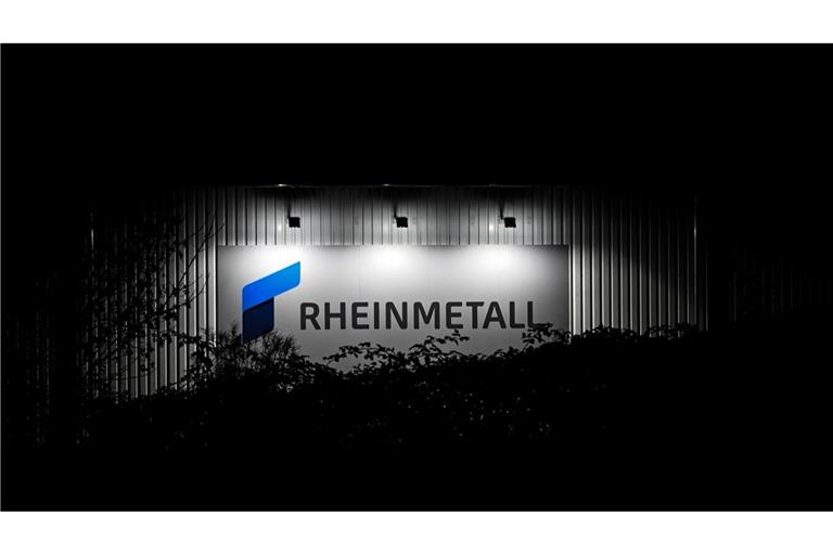 Das beleuchtete Logo und der Schriftzug der Rüstungsfirma Rheinmetall hängt an einer Produktionshalle.