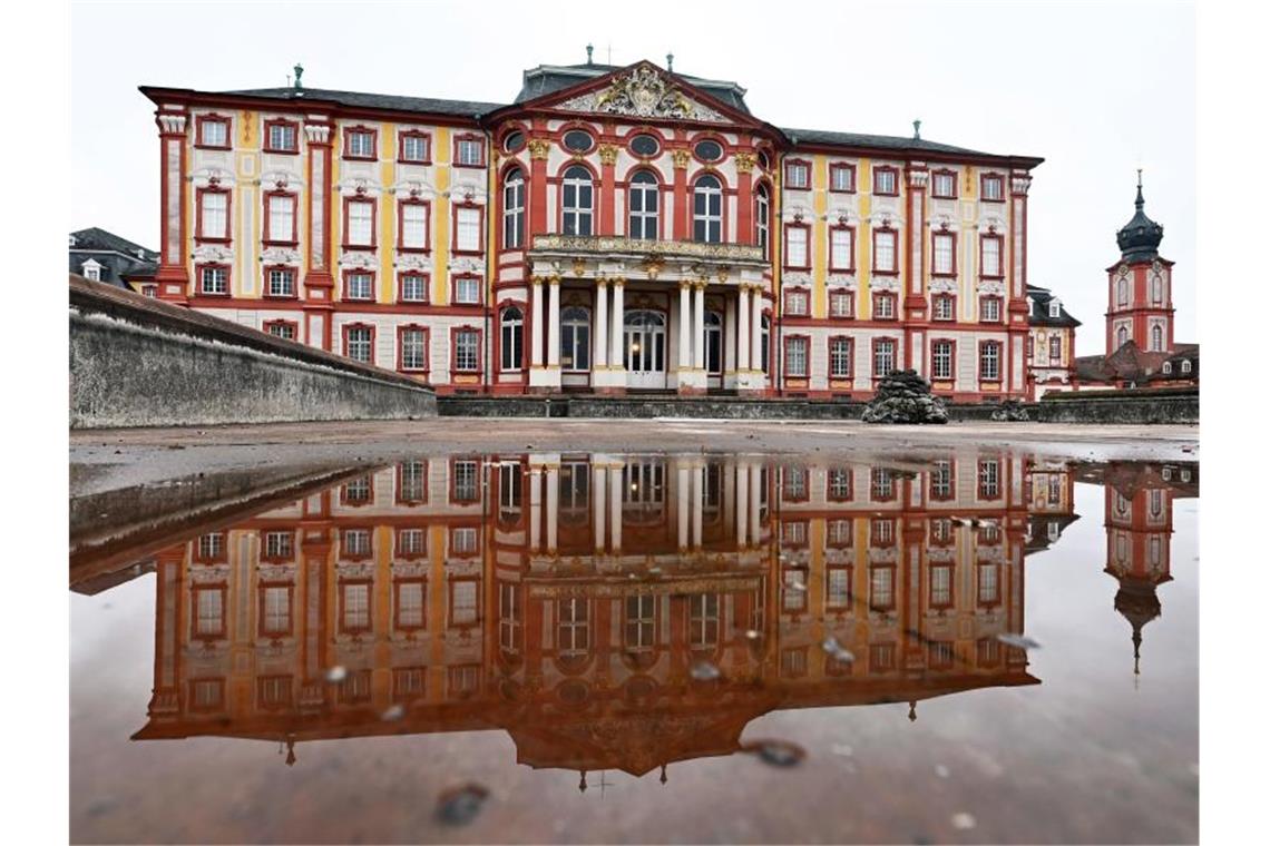 Das Bruchsaler Schloss spiegelt sich in einer Pfütze. Foto: Uli Deck/dpa/Archivbild