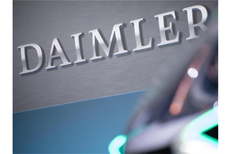 Das Daimler-Konzernlogo ist hinter einem Auto zu sehen. Foto: Sebastian Gollnow/Archivbild