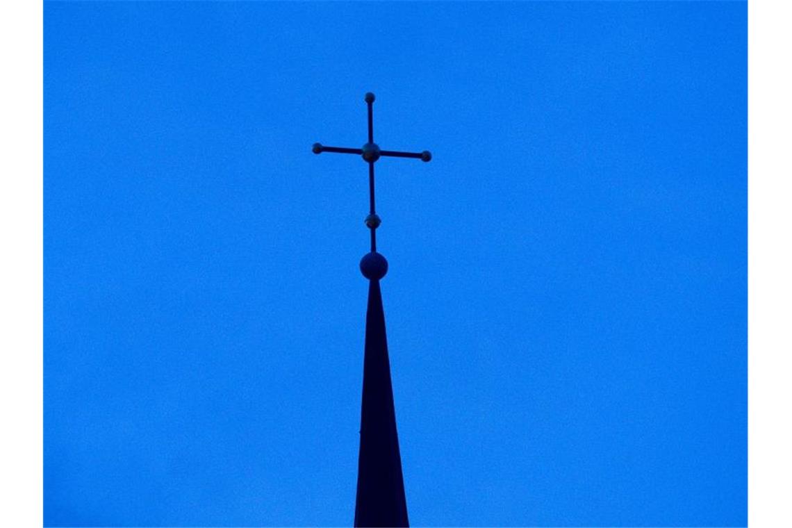 Bedford-Strohm sieht Versäumnisse seiner Kirche Das Kreuz einer evangelisch-lutherischen Kirche in der Abenddämmerung. Foto: Friso Gentsch/dpa
