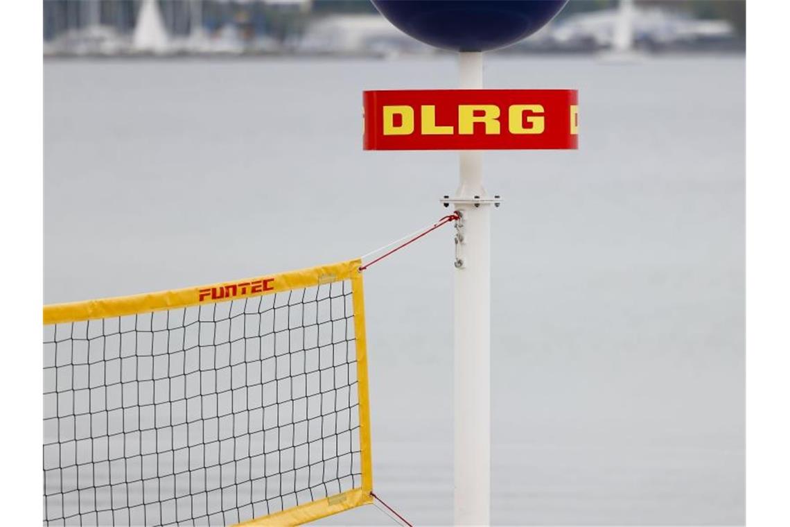 Das Logo der Deutschen Lebens-Rettungs-Gesellschaft (DLRG) ist an einem Mast am Strand befestigt. Foto: Frank Molter/dpa/Symbolbild