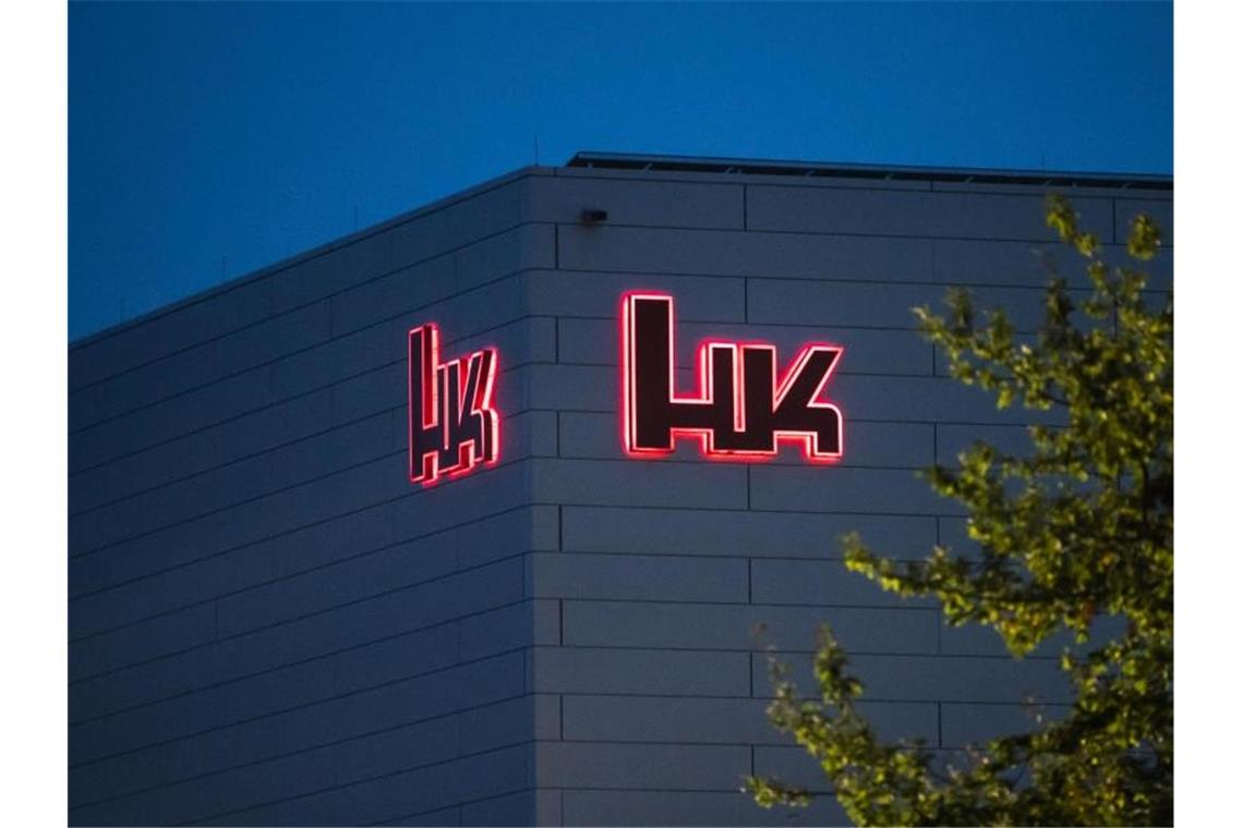 Das Logo des Waffenherstellers Heckler & Koch leuchtet bei Tagesanbruch. Foto: Silas Stein/dpa/Archivbild