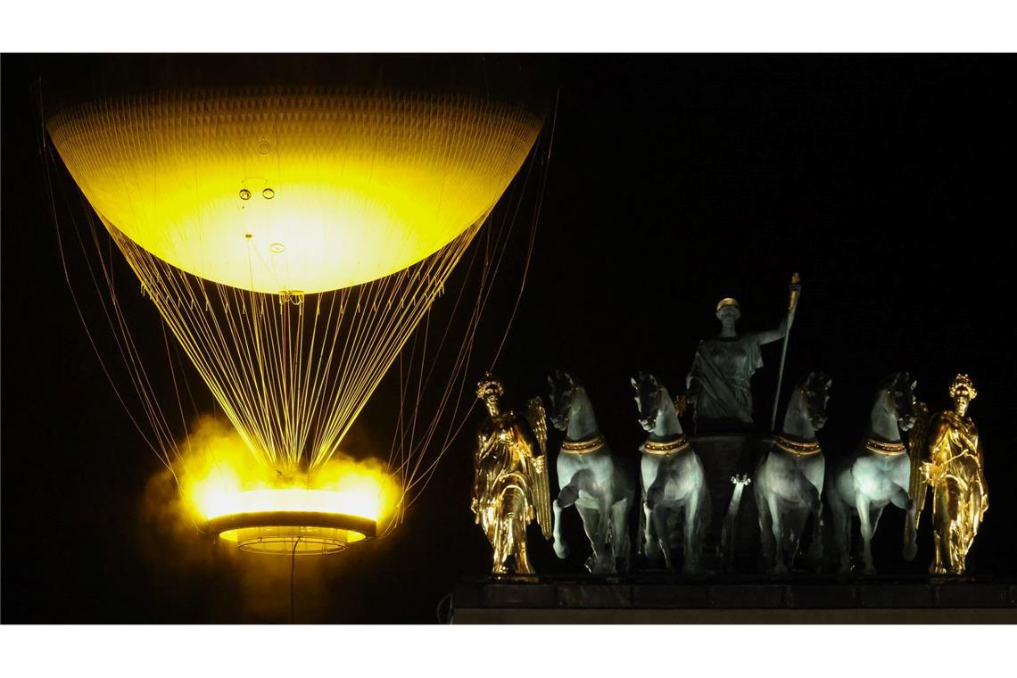 Das Olympische Feuer schwebt hinter der Statue der Quadriga in Paris.