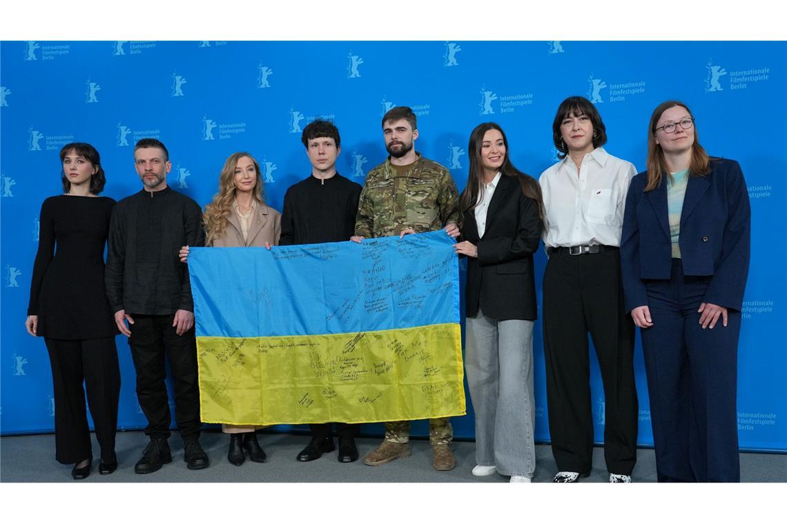 Das Team des Films "Strichka chasu" mit einer ukrainischen Flagge, auf der die Lehrerkollegen des Protagonisten und jetzigen Soldaten Borys Khovriak (M) unterschrieben haben.