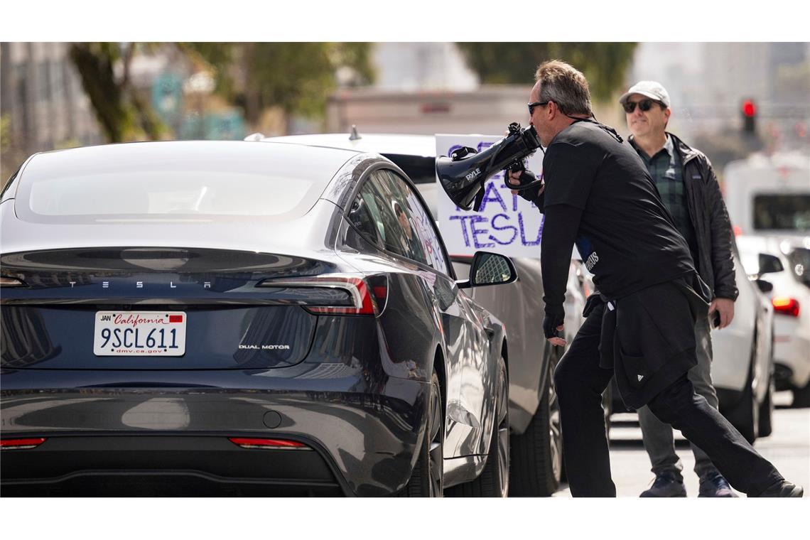 Demonstranten belästigen einen Tesla-Fahrer während einer Kundgebung vor einem Tesla-Händler in San Francisco.