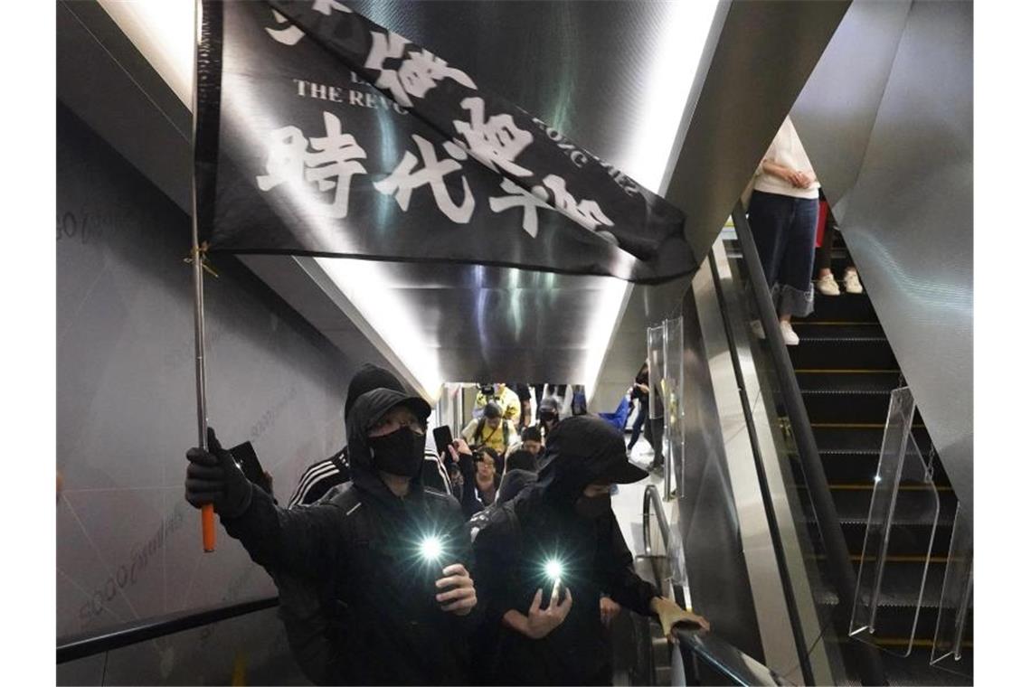 Zusammenstöße überschatten Weihnachten in Hongkong Demonstranten mit Mundschutz tragen eine Flagge mit der Aufschrift „Befreit Hongkong, die Revolution unserer Zeit“ in einem Einkaufszentrum. Foto: Vincent Yu/AP/dpa
