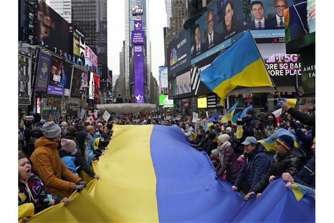 Demonstranten stehen um eine große ukrainische Flagge versammelt auf dem Times Square, um gegen die russischen Angriffe auf die Ukraine zu protestieren. Foto: Seth Wenig/AP/dpa