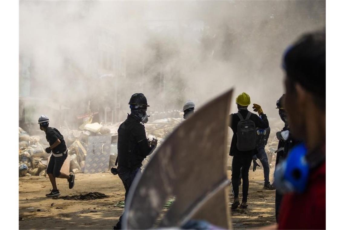 Seit Putsch in Myanmar mindestens 138 Demonstranten getötet Demonstranten stehen vor rauchenden Trümmern einer provisorischen Barrikade bei einem Anti-Putsch-Protest in Yangon. Myanmarische Sicherheitskräfte haben heute erneut Waffengewalt gegen eine Demonstration gegen die Militärjunta eingesetzt. Foto: Uncredited/AP/dpa