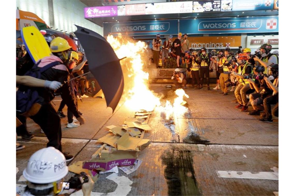 Demonstranten verbrennen Karton, um eine Barriere zu bilden. Die Polizei setzte Tränengas ein und räumte Straßen. Foto: Kin Cheung/AP