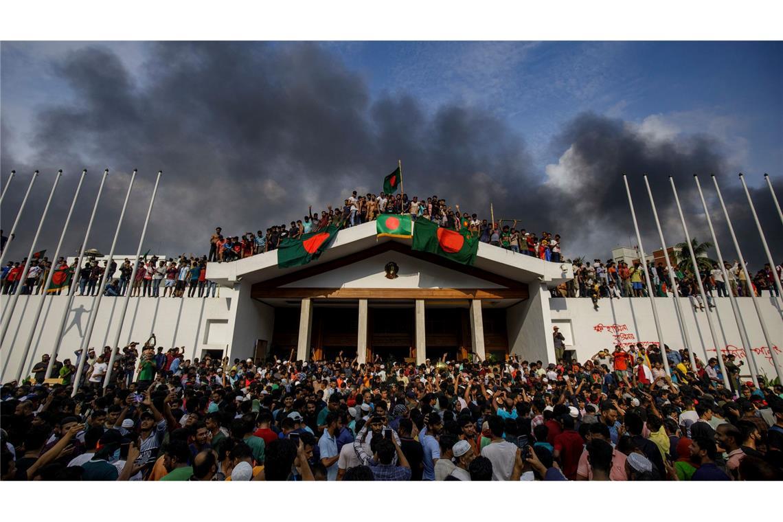 Demonstranten versammeln sich am Palast der Premierministerin Hasina in Dhaka, den sie zuvor gestürmt haben. Hasina war zurückgetreten, nachdem Tausende von Demonstranten eine Ausgangssperre des Militärs missachtet und ihren Amtssitz gestürmt hatten.