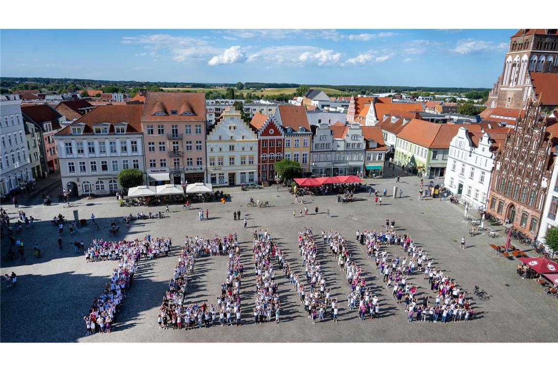 Den Namen Toni bilden Einwohner aus Greifswald in weißen und rosa Trikots auf dem Marktplatz von Greifswald udn ehren damit den Fußball-Natiuonalspieler Toni Kroos. Greifswald ist Kroos' Geburtsstadt