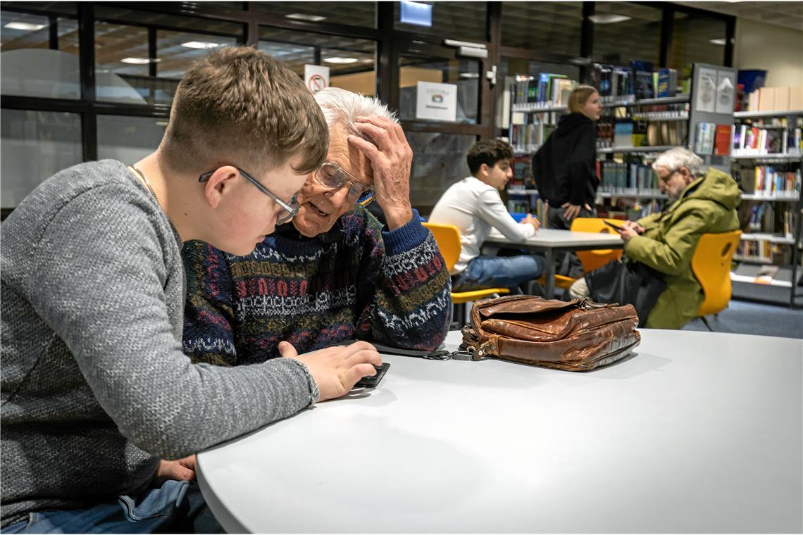 Der 14-jährige Daniel Schnell erklärt dem 94-jährigen Helmut Reinhardt, wie er eine App auf seinem Handy löschen kann. Foto: Alexander Becher