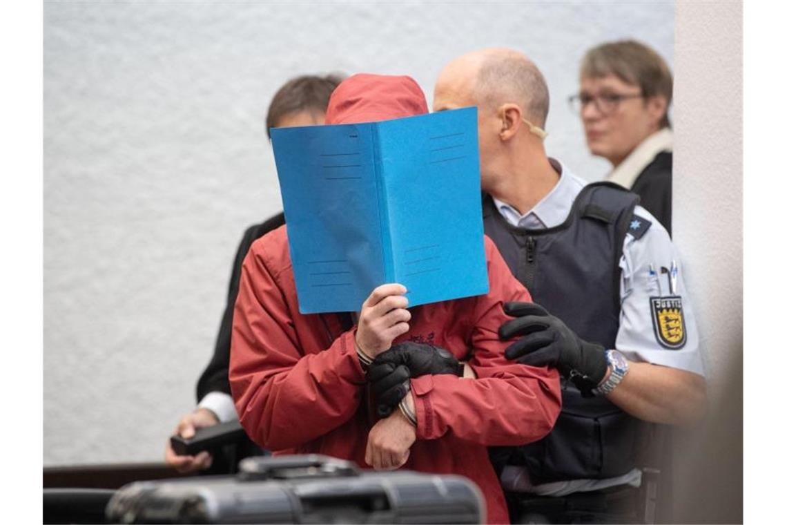 Tränen im Gericht: Mutmaßlicher Raser schildert Unfall Der Angeklagte in einem Mordprozess nach einem tödlichem Unfall wird von einem Justizbeamten in einen Gerichtssaal des Landgerichts Stuttgart geführt. Foto: Marijan Murat/dpa
