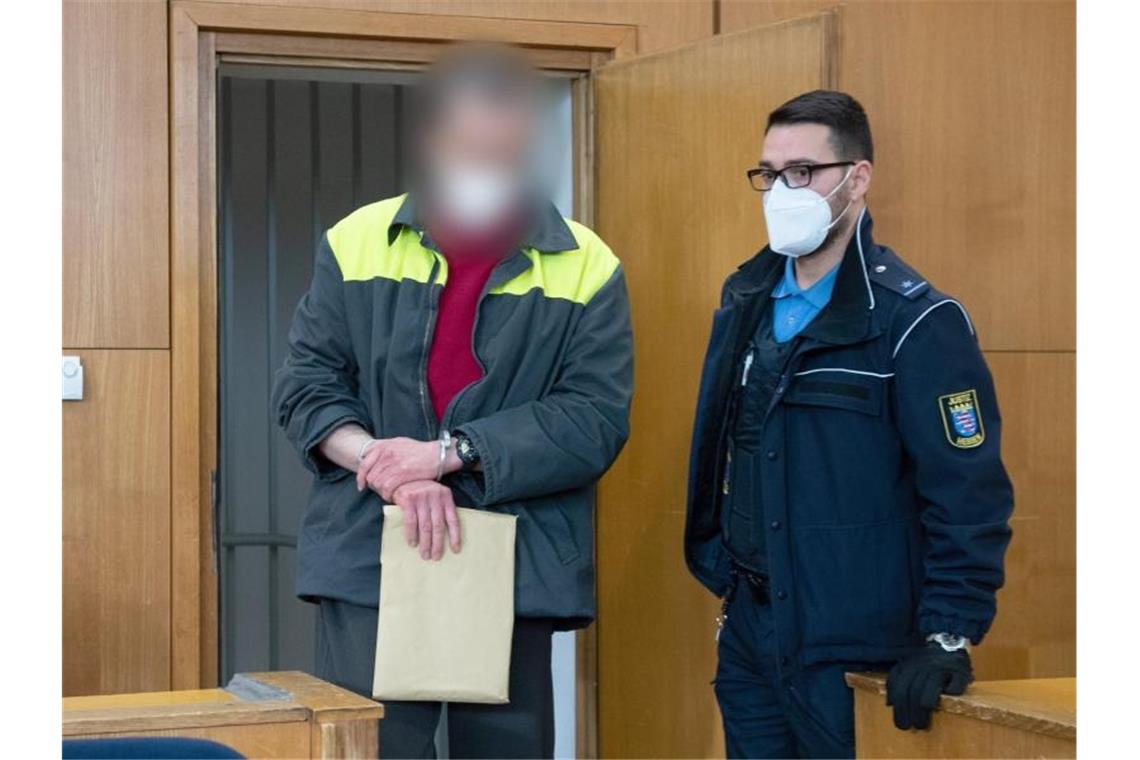 „NSU 2.0“-Prozess: Angeklagter bestreitet Vorwürfe Der Angeklagte und mutmaßliche Verfasser der „NSU 2.0“-Drohschreiben wird mit Handschellen in den Verhandlungssaal geführt. Foto: Boris Roessler/dpa Pool/dpa