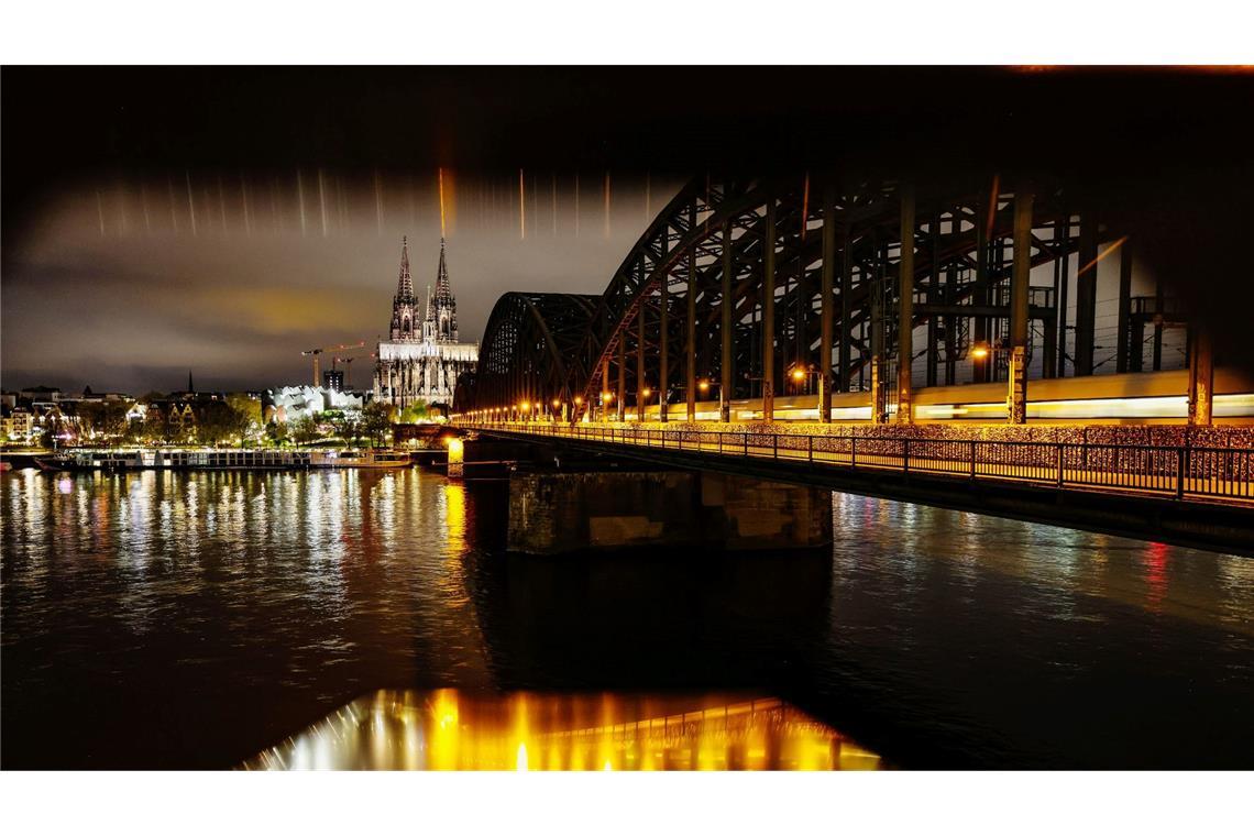Der beleuchtete Kölner Dom und die Hohenzollernbrücke am frühen Morgen.