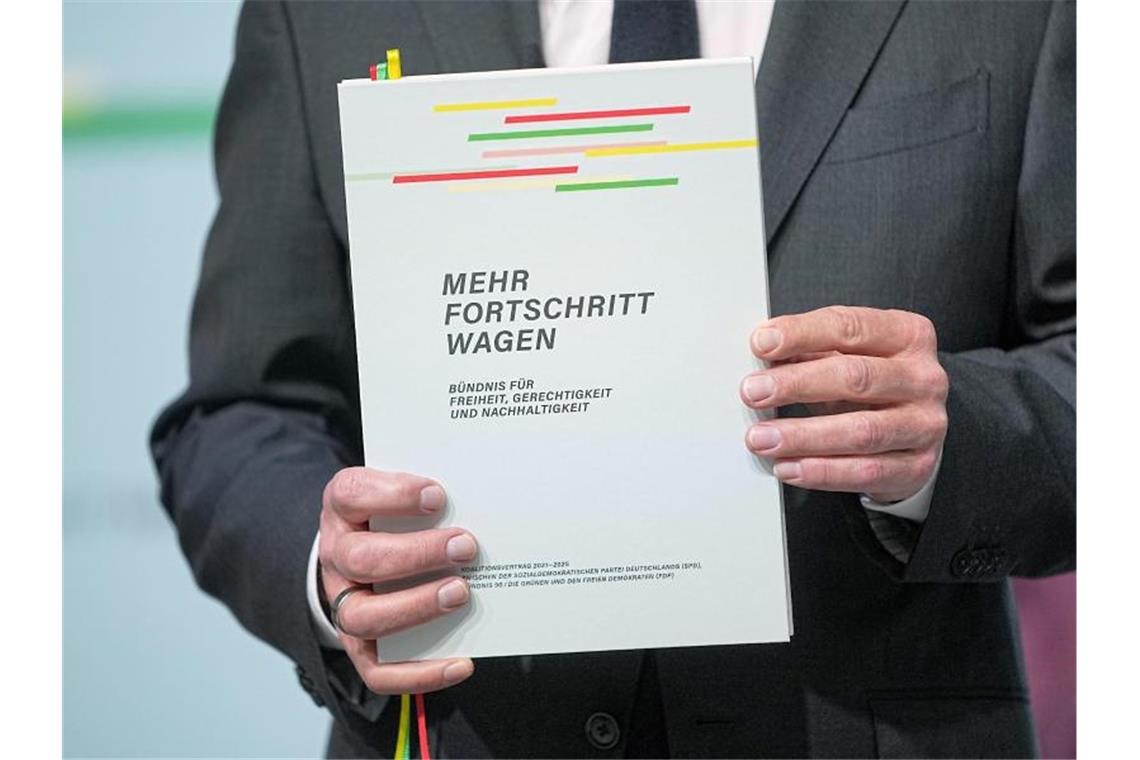 Koalitionsvertrag unterzeichnet: Ampel-Bündnis steht Der designierte Bundeskanzler Olaf Scholz mit dem Vertrag seiner Regierungskoalition. Foto: Michael Kappeler/dpa
